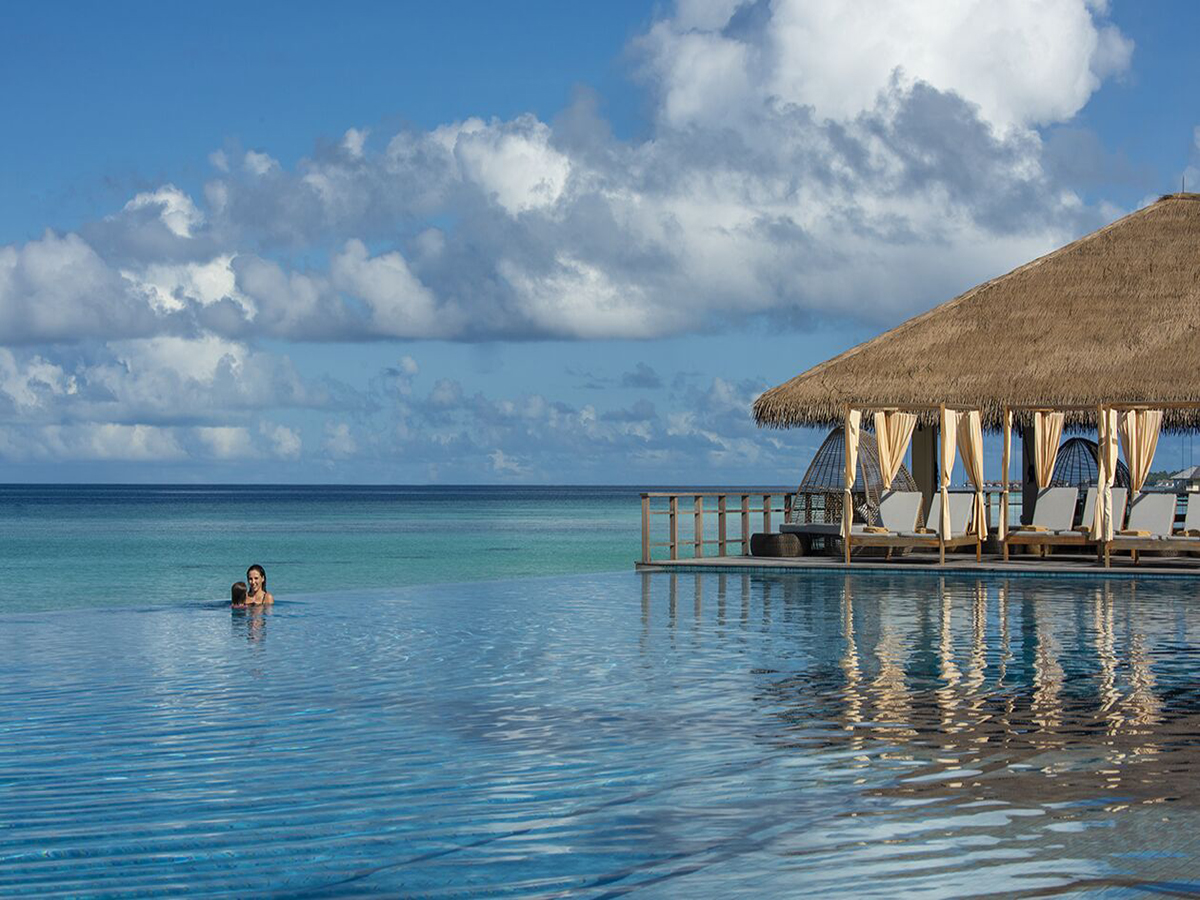 Piscina infinity principal de The Residence Maldives at Dhigurah frente a la laguna