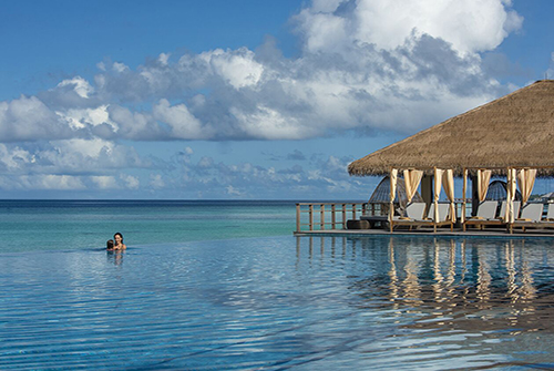 Piscina infinity principal de The Residence Maldives at Dhigurah frente a la laguna