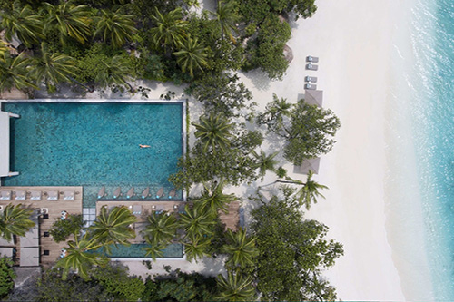 Piscina principal y playa de arena blanca en Vakkaru Maldives